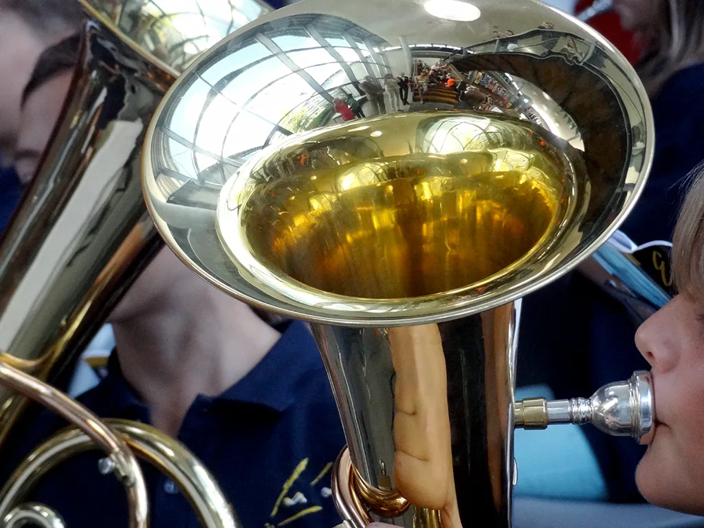 Nahaufnahme eines Tenorhorns, dahinter Musizierende.